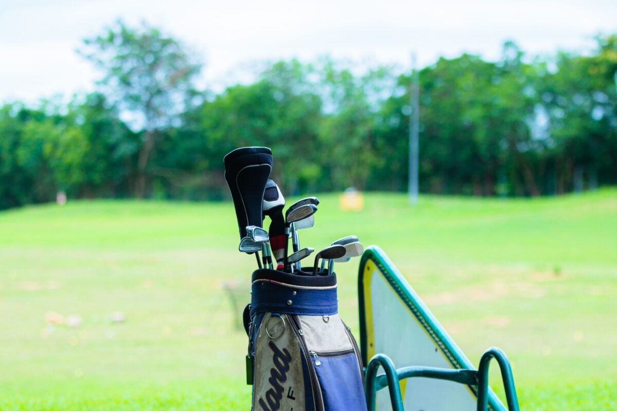 A golf bag and clubs standing at a driving range