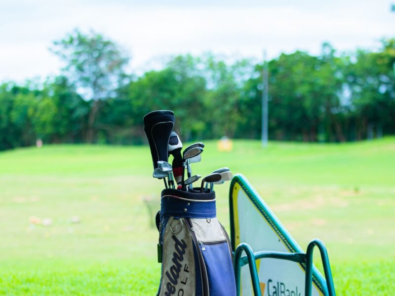 A golf bag and clubs standing at a driving range