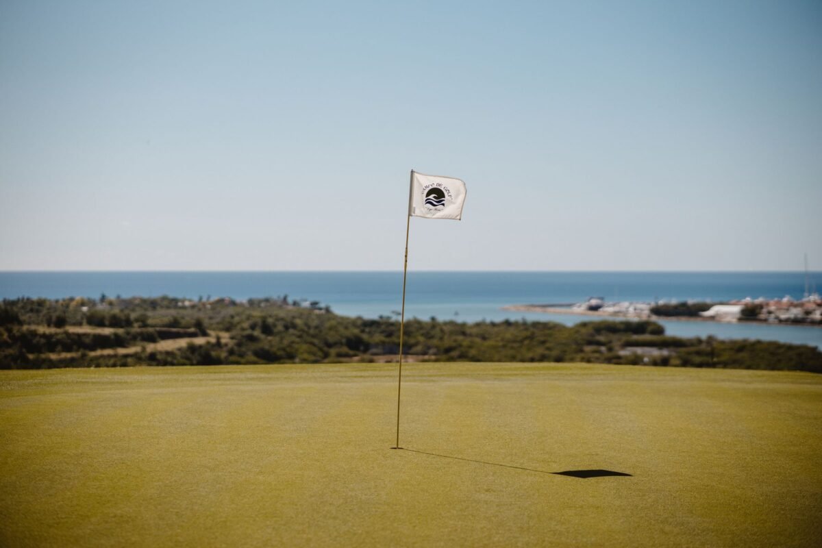 A white flag on a green beside the sea