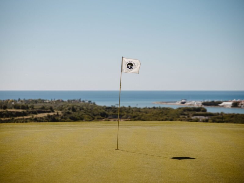 A white flag on a green beside the sea