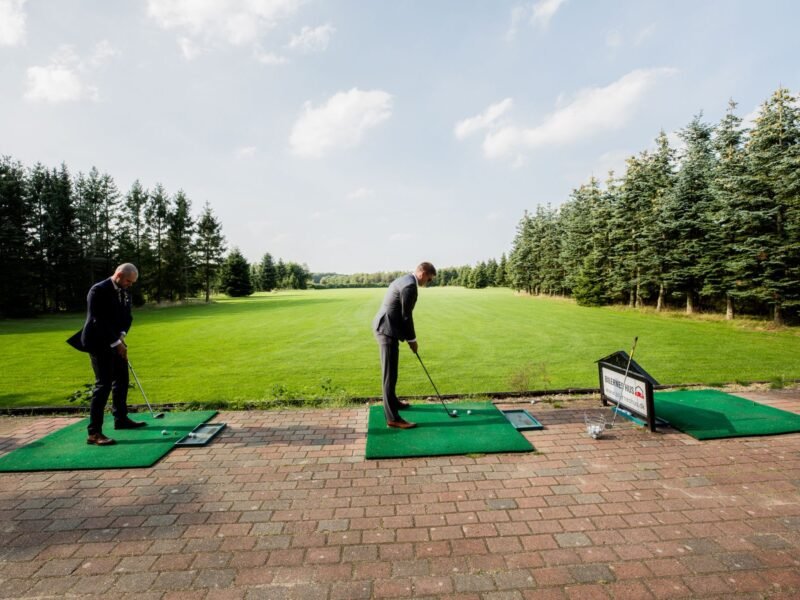 Two men in business dress playing a round of golf together