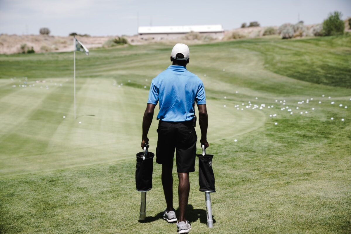 A caddy carrying golf bags along the fairway