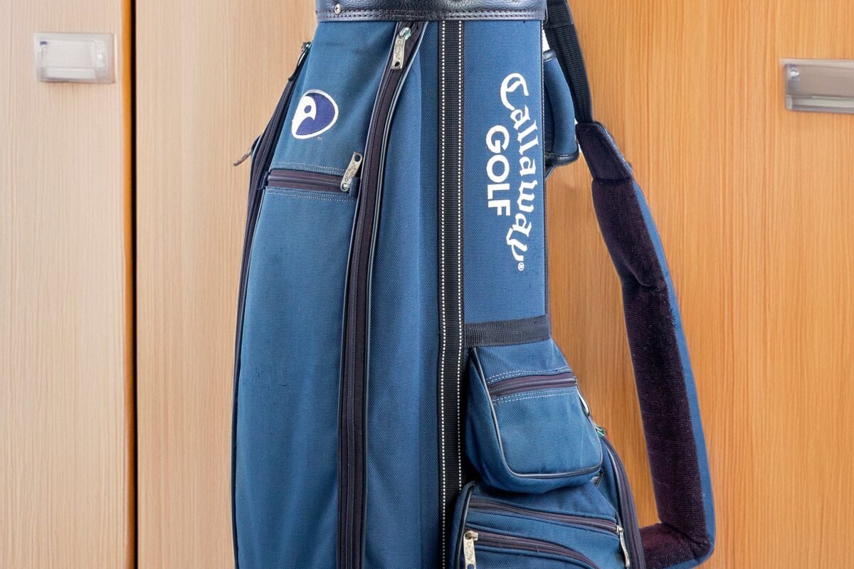 A blue golf bag full of clubs standing in an indoor locker room