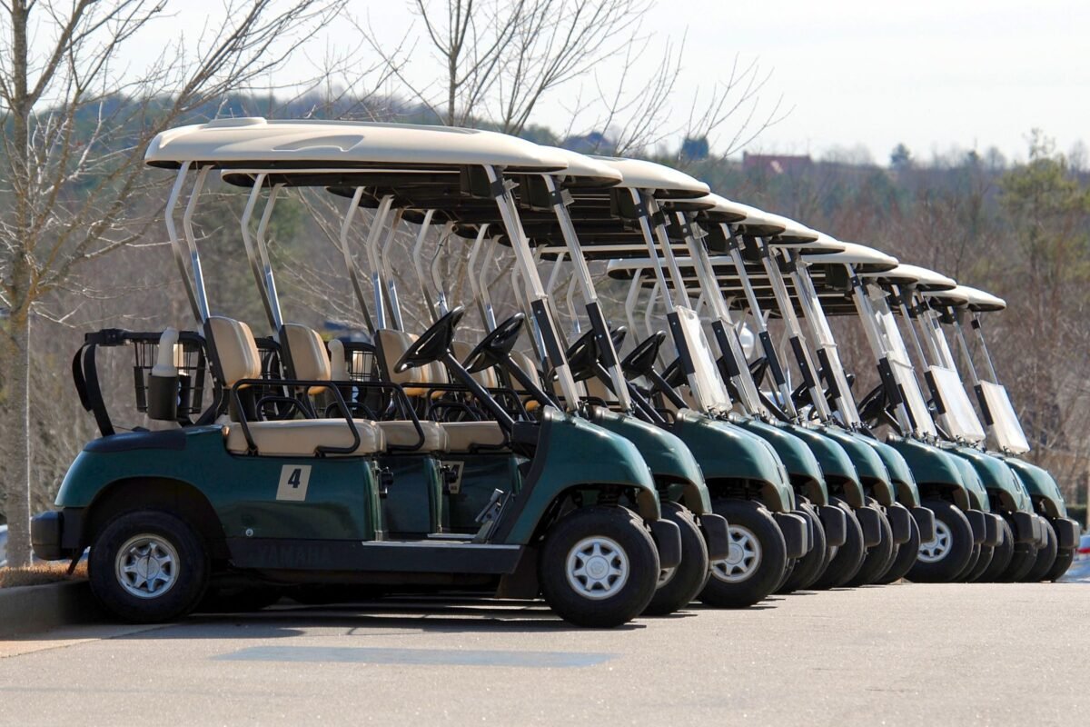 A fleet of blue and white golf carts parked in a row