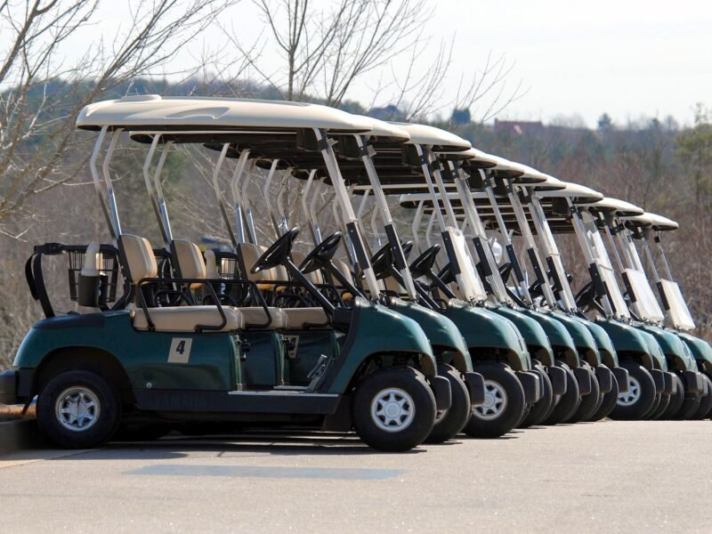 A fleet of blue and white golf carts parked in a row