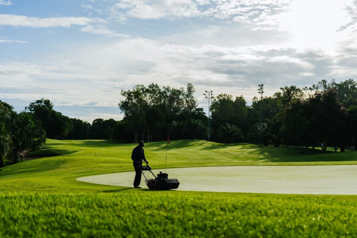 A greenkeeper mowing a fairway on a golf course