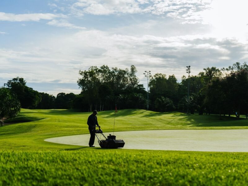 A greenkeeper mowing a fairway on a golf course