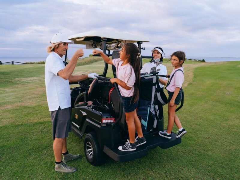 An adult and a child bumping fists on a golf course