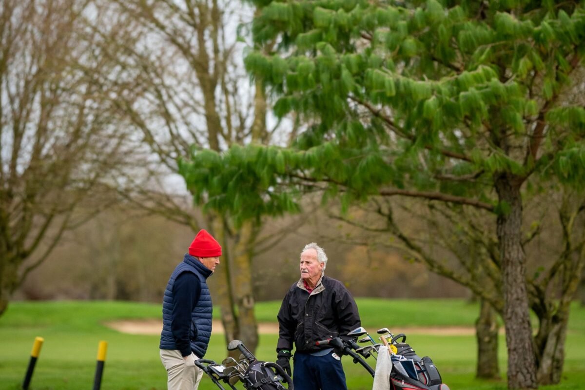Older members talking beside their golf bags on the grass