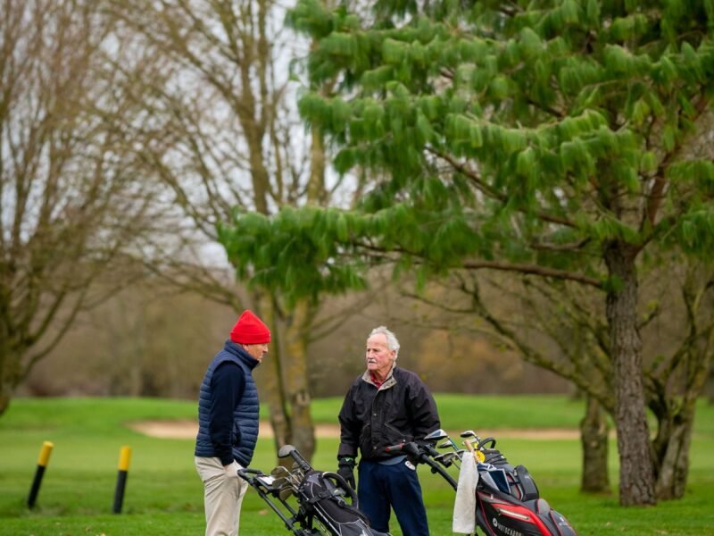 Older members talking beside their golf bags on the grass