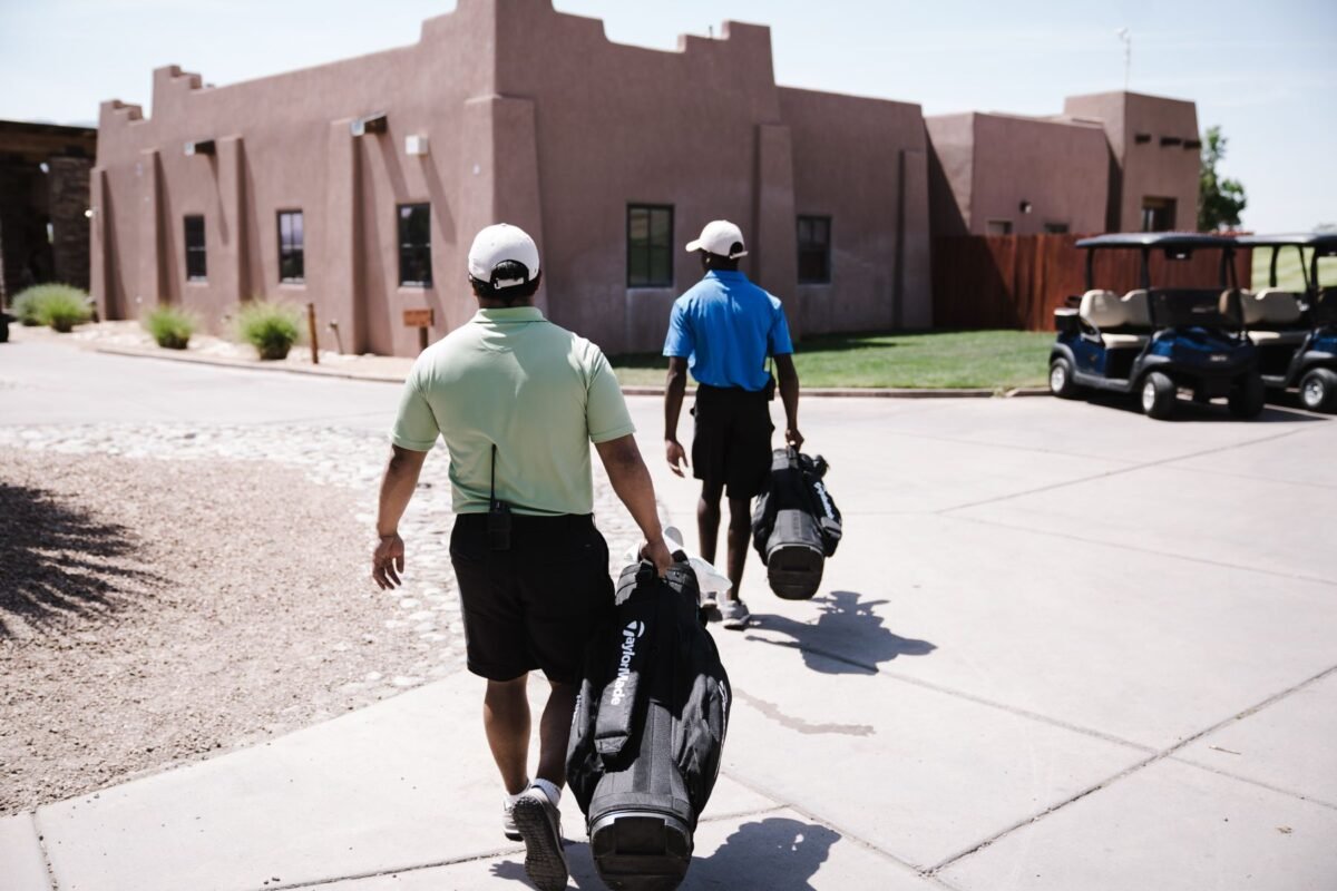 Two players carrying their golf bags on the course