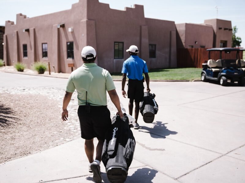 Two players carrying their golf bags on the course