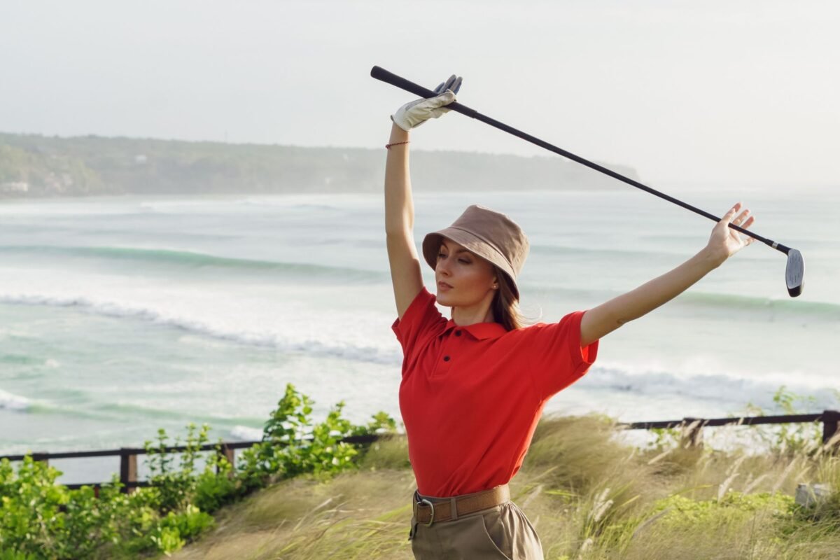 A woman in a golf shirt holding a club on the course