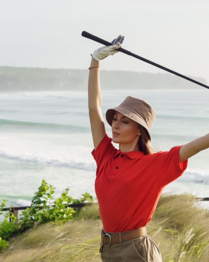 A woman in a golf shirt holding a club on the course