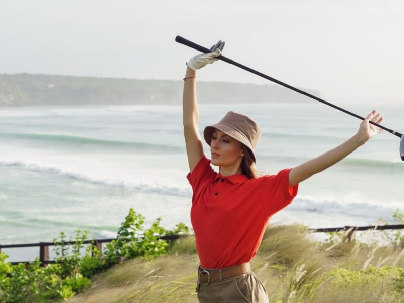 A woman in a golf shirt holding a club on the course