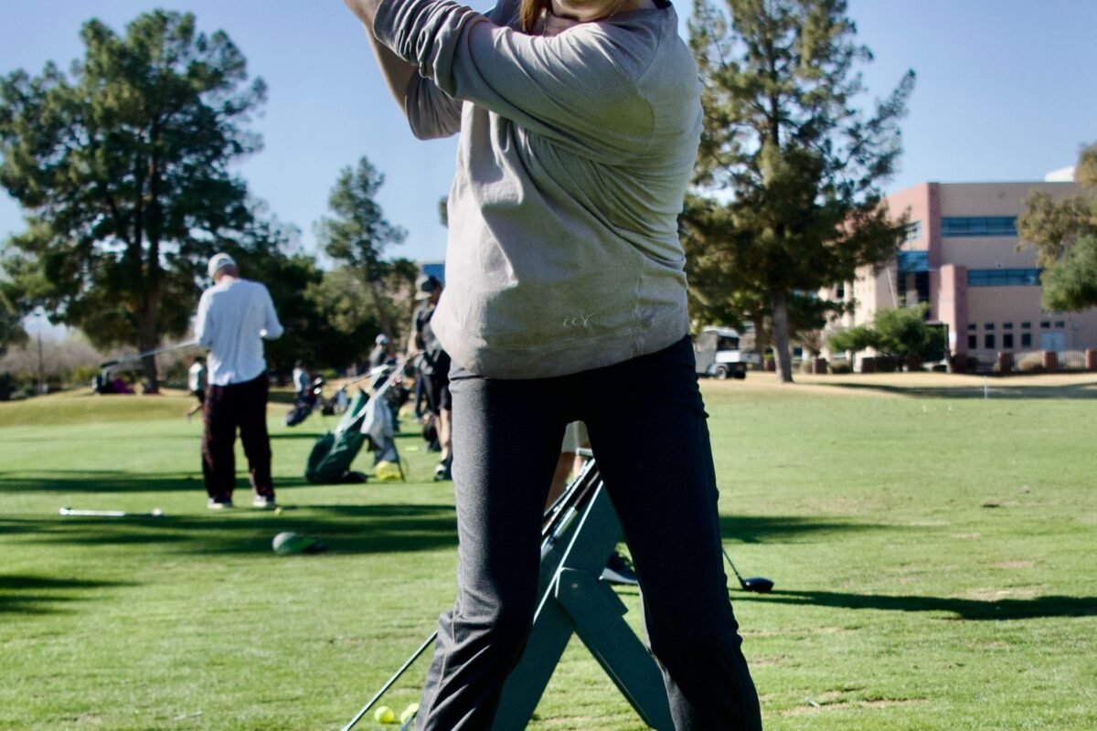A woman playing a shot on a golf course