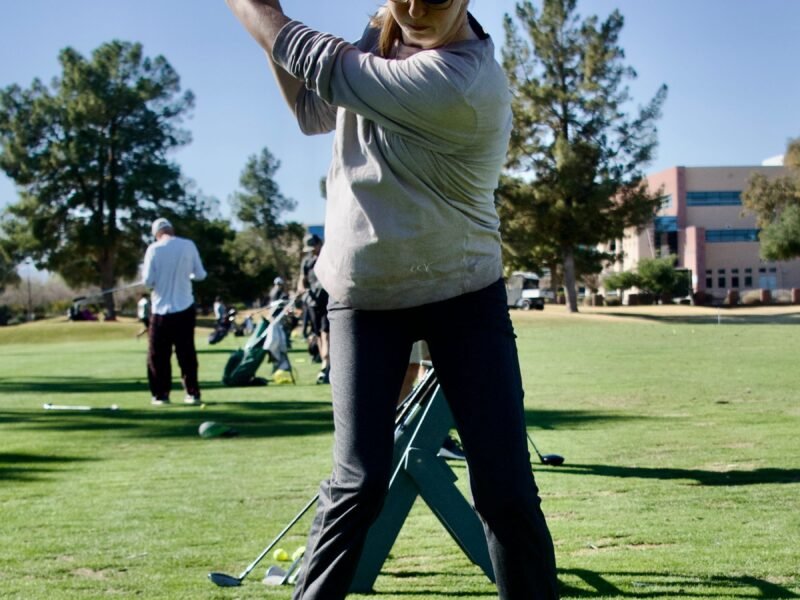 A woman playing a shot on a golf course
